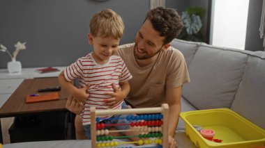 Baba ve oğul oturma odasında eğitici oyuncaklarla oynuyorlar. İçeride aile bağlarını kuvvetlendiriyorlar.