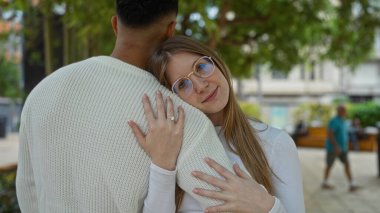 Kadın açık şehir parkı ortamında erkeği kucaklıyor, beraberliği ve aşkı sakin ve güzel bir atmosferle sergiliyor, ilişki temalı görseller için mükemmel..