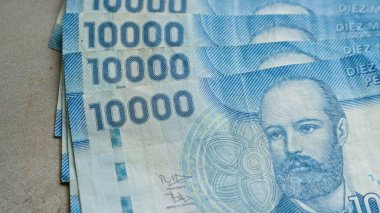 Şili banknotları arka arkaya on bin pezoluk banknotlar halinde düzenlenmiştir. Karmaşık tasarımlarını ve mavi tonlarını vurgular..