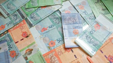 Düz bir zemine saçılmış renkli Malezya bankaları, Malezya 'nın canlı para birimini çeşitli değerlerle vurguluyor..