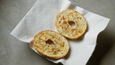 Beton bir yüzey üzerinde kağıt havlunun üzerinde oturan kızarmış simit parçaları altın dokularını ve çıtır çıtır kenarlarını renklendiriyor..