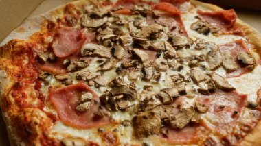 Jambon, mantar ve altın peynirle kaplanmış lezzetli çıtır pizzalar, İtalyan mutfağının özünü ağız sulandıran yakın plan çekimde yakalıyor.