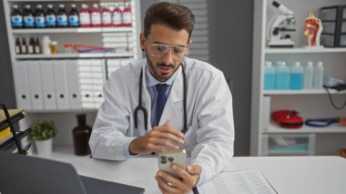 Doktor, klinik ortamında beyaz önlüklü, tıbbi ekipmanlı genç bir İspanyol 'un görüntülerini gösteriyor..