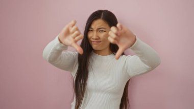 Kadın, kendinden emin bir ifadeyle onaylamayarak baş parmak hareketi yapıyor. Canlı pembe bir arka plana karşı izole bir şekilde duruyor..