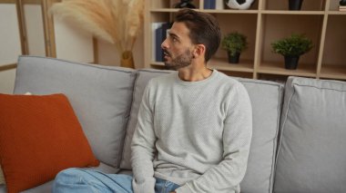 Modern dekorlu, rahat ev atmosferini yansıtan şık bir apartman dairesinde oturan İspanyol genç adam..