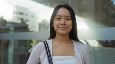 Genç Çinli bir kadın şehir caddesinde duruyor, güzel, çekici ve kendine güvenen varlığıyla Çin 'in hareketli şehir yaşamını sergiliyor..