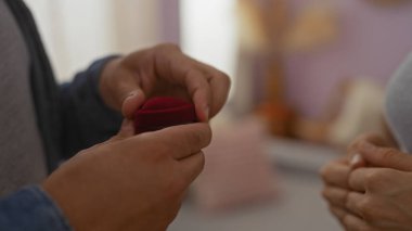 Adam, elinde yüzük kutusu olan bir kadına samimi ve romantik bir ortam yaratarak evlenme teklif ediyor.