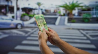 Arka planda bulanık şehir manzarası olan bir şehir sokağında Güney Afrika rand banknotlarını sayan bir adam..