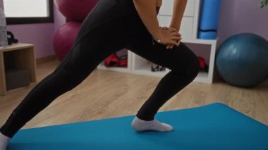 Kadınlar spor salonunda yoga minderiyle, egzersiz topuyla ve modern iç fitness merkezinde ekipmanla esniyorlar..