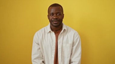 Afro-Amerikalı adam ayakta dikiliyor ve havada bir öpücük savuruyor izole edilmiş sarı arka planda sevimli ve seksi bir ifadeyle.