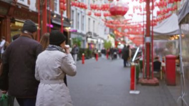 İnsanlar Londra 'nın canlı Chinatown caddesinde geziniyor serin sonbahar havasının ortasında şenlikli fenerlerle süslenmiş.