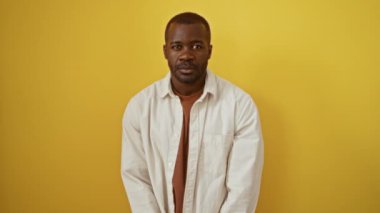 Ezik jest, Afro-Amerikan tişört giyen, parmakları alnında duran, izole edilmiş sarı arka planda insanlarla alay eden ve aşağılayan