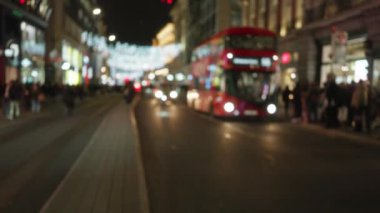 Londra 'daki sokak sahnesi. Odaklanamayan ışıklar, bulanık kırmızı otobüs ve kış boyunca hareketli gece atmosferi..