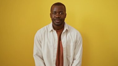 İş ortamında tişört giyen, gülümseyen Afrikalı Amerikalı adamın el sıkışması. İzole edilmiş sarı arka planda başarılı bir selamlaşma.