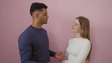 İzole edilmiş pembe bir arka plana karşı birlikte duran erkek ve kadın güzel bir ilişkiyi yansıtan sevgi dolu bir sohbete girişiyor.