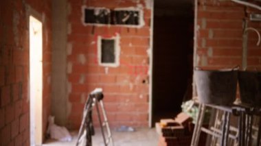 Tamamlanmamış bir inşaat projesi sırasında odakları kesilmiş tuğla kovaları ve ekipmanlarıyla bulanık inşaat sahası