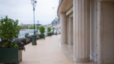 Monaco 'daki açık hava sahnesinde sütunları, yeşillikleri ve sokak lambaları olan bulanık bir lüks cadde var. Odaklanmamış bir perspektifte, zarafet ve bolluk hissi yakalıyor..