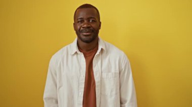 Sarı arka planda dili dışarıda dikilen Afro-Amerikalı bir adam. Eğlenceli, neşeli ve anlamlı bir jestle yakalanmış.