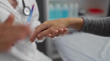 Muayene sırasında bir klinikte tedavi ve güvenin altını çizen nazik bir dokunuşla hastayı rahatlatan doktor..