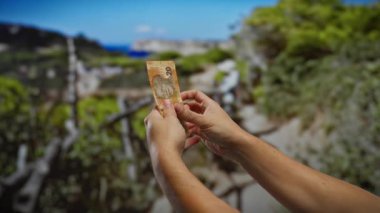 Güney Afrika Rand banknotlarını elinde tutan adam bir açık hava parkı ortamında, para ve iş etkileşimine odaklı kentsel, doğal bir çevre yakalıyor..