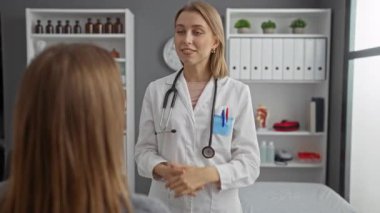 Kadın doktor, modern klinikteki hastalarla konuşuyor. Raflarda tıbbi malzemeler var.