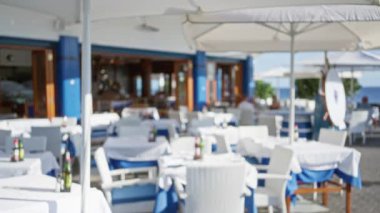 Ianzarote 'deki bir açık hava restoranının bulanık manzarası. Odaklanmış masaları ve şemsiyelerin altında sandalyeleri var. Kanarya adalarında okyanus kenarında, İspanya.