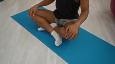 Adam spor salonundaki yoga minderinde meditasyon yapıyor.