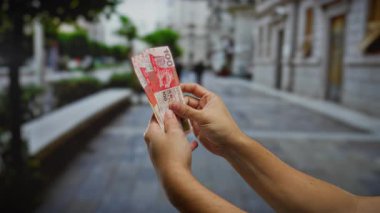 Şehir sokaklarında Hong Kong Doları banknotları tutan adam açık şehir ortamında yatırım ve finansman öneriyor..