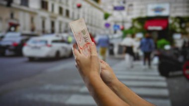 Yoğun bir şehir caddesinde tek başına dolar sayan kişi, şehir yaşamındaki mali faaliyetleri vurguluyor..