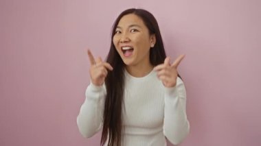 Pembe arka planda neşeli bir ifadeyle işaret eden genç kadın, neşeli enerji ve bağlantıyı yakalıyor..