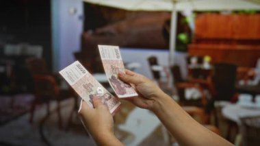 Kentsel açık kafe ortamında yatırım kavramını vurgulayan İzlanda Krona el ele tutuşması, para birimi ve iş unsurlarının yer aldığı.