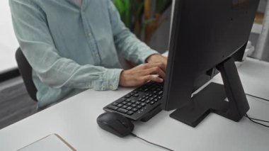 Modern ofiste bilgisayar kullandıktan sonra dinlenen genç adam, doğal ışık ve yeşillikle sakin bir çalışma alanı sergiliyor, barışçıl bir çalışma ortamını somutlaştırıyor..