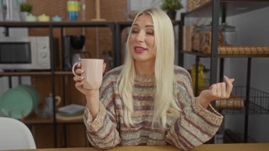 Raflar, renkli bardaklar ve arka planda mikrodalga fırın olan rahat bir mutfak ortamında el kol hareketi yapan bir kadın..