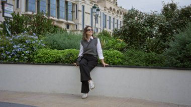 Monaco 'da açık havada oturan bir kadın yemyeşil ve zarif mimarisi olan lüks bir ortamın tadını çıkarıyor..