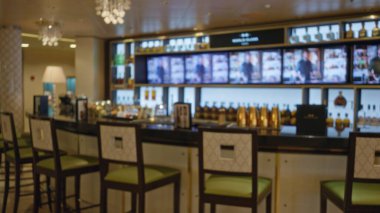 Bulanık odak noktalı lüks çubuk iç mekanı zarif dekorasyon ve canlı atmosferi vurguluyor, gelişmiş bir kapalı mekan deneyimi için lüks koltuklar ve şık ışıklandırma sergiliyor.