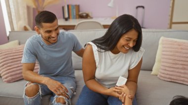 Gülümseyen İspanyol çift, sıcak bir oturma odasında aileleriyle güzel vakit geçiriyorlar. Sevgi ve birliktelik yayıyorlar..