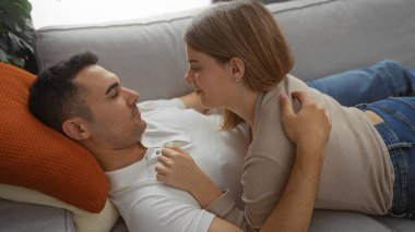 Sıcak bir oturma odasında birlikte dinlenen, erkeğin üzerine uzanan, huzurlu bir evde sevgisini ve mutluluğunu ifade eden, rahat bir koltukta birbirini kucaklayan bir çift..