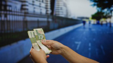 Bir şehir caddesinde Hong Kong doları sayan bir adam, bir şehir ortamında finansal faaliyet ve yatırım anını yakalıyor..