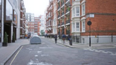 Kışın kalabalık bir Londra caddesinin bulanık yayaları ve sembolik İngiliz mimarisi şehir yaşamını ve mevsimsel ambiyansı vurguluyor..