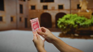 Şehrin bir caddesinde Çin Yuan banknotları tutan adam şehir merkezinde tarihi bir arkaplanı bulanık ekonomik faaliyetleri yansıtıyor..