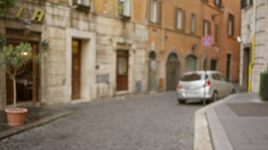 Roma 'da bulanık bir sokak sahnesi. Odakları çözülmüş arka plan ve kaldırım taşı yolu, eski binalar ve İtalya' da açık havada bir araba görünüyor..