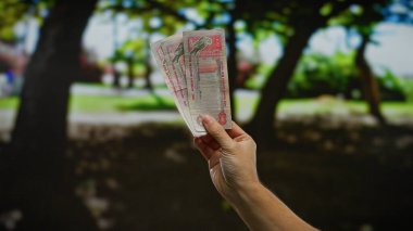 Şehir parkında elinde Dirham banknotları tutan bir adam, şehir dışı unsurları ve döviz kurları ile bir iş konseptini vurguluyor..