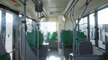 Yeşil koltuklu içi boş bir otobüsün bulanık görüntüsü, çözülmüş bokeh ışıkları ve sakin, sakin bir ulaşım ayarları.