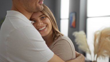 İspanyol çift sıcak bir oturma odasında sevgi ve sıcaklığı modern ev ortamında mutlu ifadelerle paylaşıyor derin bir bağ ve ahenk öneriyor.