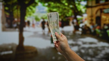 Şehir merkezinde bulanık insanlar ve yeşilliklerle dolu işlek bir caddede kirli paralarla el ele tutuşmak..