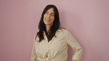 Soyutlanmış pembe arka planda mutlu bir şekilde gülümseyen genç kadın.