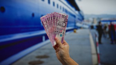 Filipinli pezoların el ele tutuşması deniz kıyısındaki bir liman limanında büyük bir tekne ile para göstermesi finans, yatırım ve seyahat temalarını yansıtıyor..