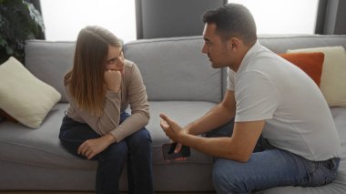 Sıcak bir oturma odasındaki kanepede oturan erkek ve kadın, düşünceli ifadelerle ciddi bir sohbete girişirler, bir bağ kurma ve anlayış gösterirler..