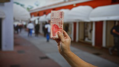 Kentsel bir sokak ortamında bir yığın Tayvan doları tutan adam, hareketli bir şehir ortamında yatırım ve finansmanı vurguluyor..