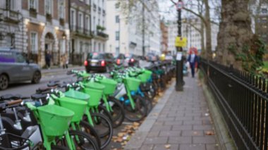 Bisikletler, Birleşik Krallık 'ta kentsel yaşam ve ulaşımı gösteren bulanık arabalar ve yayalarla sonbaharda dağılmış bir Londra caddesinde dizilmiş..